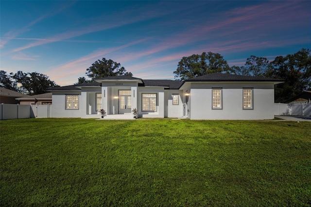 back house at dusk featuring a yard