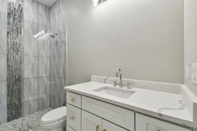 bathroom featuring tiled shower, vanity, and toilet