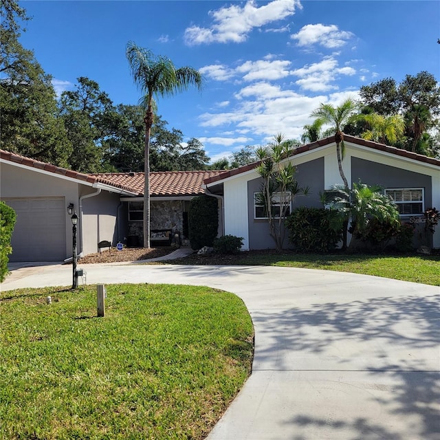 view of front of home with stucco siding, a front lawn, driveway, an attached garage, and a tiled roof