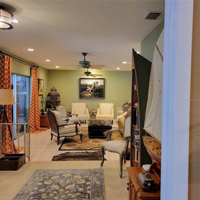 living room with ceiling fan, light tile patterned floors, and a textured ceiling