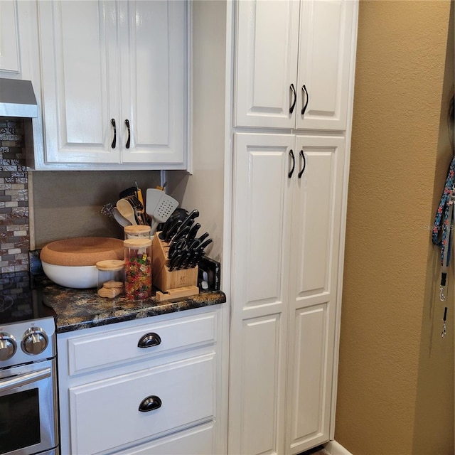 kitchen featuring extractor fan, white cabinetry, white electric range, and dark stone counters