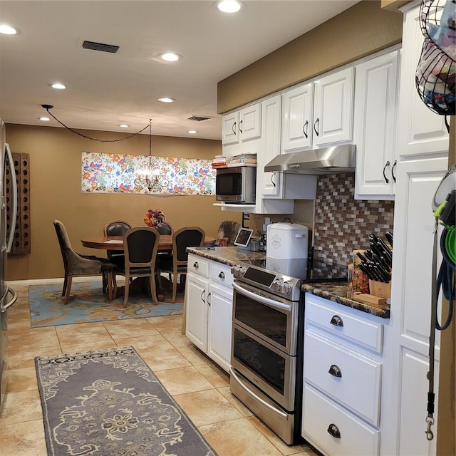 kitchen with dark stone countertops, white cabinetry, hanging light fixtures, and stainless steel appliances