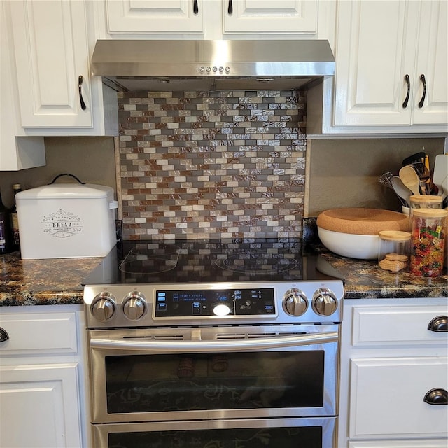 kitchen with stainless steel electric range oven, white cabinetry, decorative backsplash, and wall chimney range hood