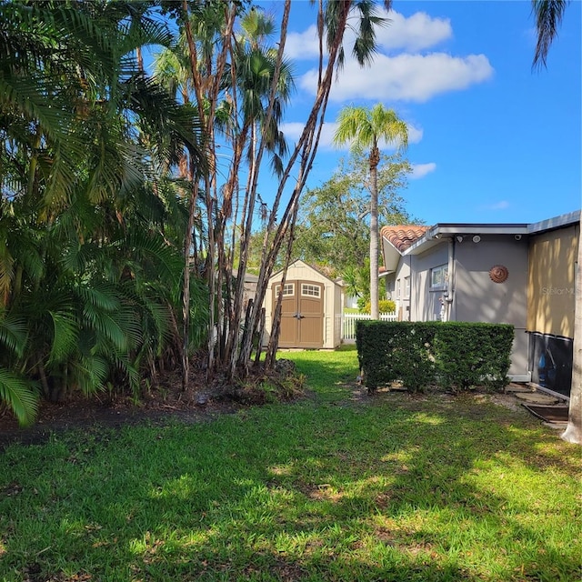 view of yard featuring a storage unit, an outbuilding, and fence