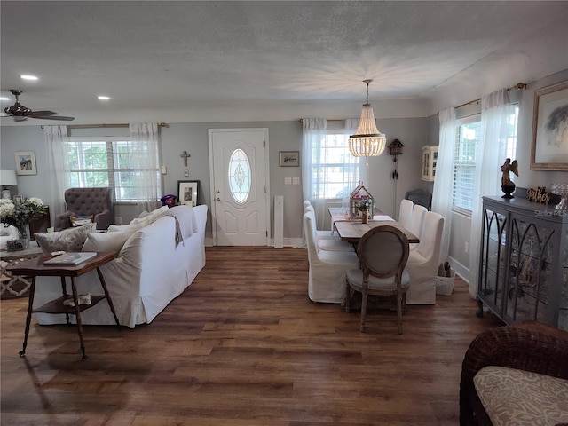 dining space with ceiling fan with notable chandelier and dark hardwood / wood-style floors