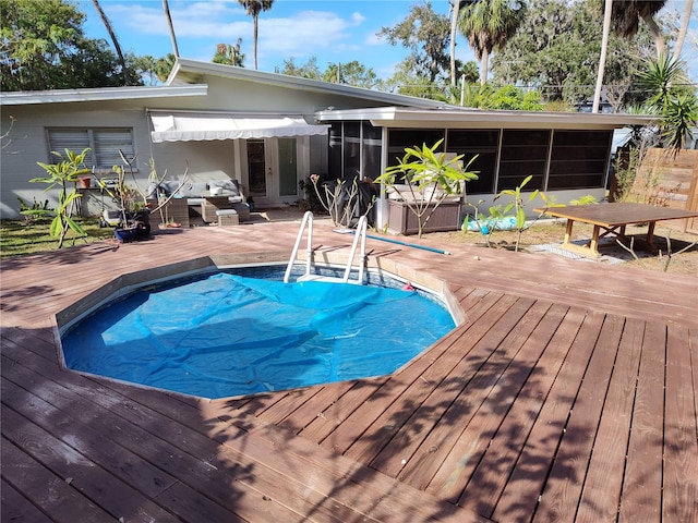 view of swimming pool with a wooden deck and a sunroom