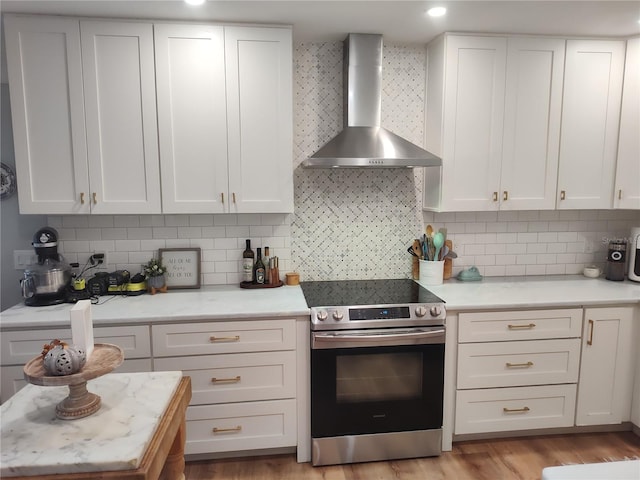 kitchen with backsplash, white cabinetry, stainless steel electric range oven, and wall chimney exhaust hood