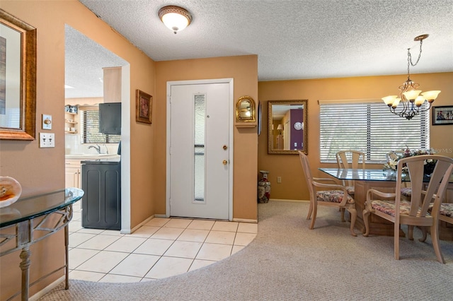 carpeted foyer entrance with a textured ceiling and a notable chandelier