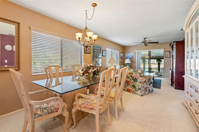 dining area with ceiling fan with notable chandelier, light colored carpet, and a textured ceiling