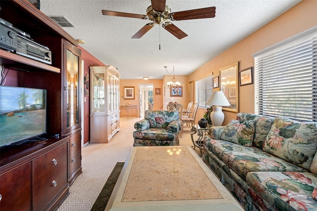 living room with a textured ceiling, ceiling fan with notable chandelier, and light carpet