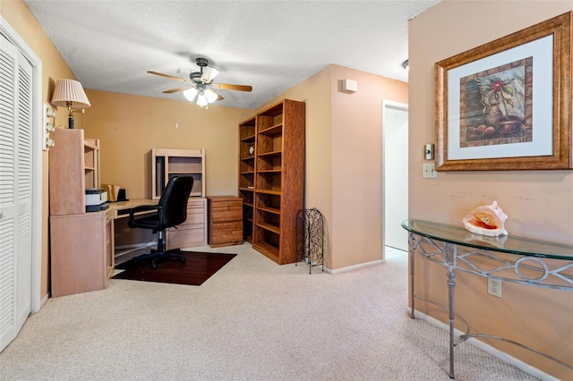 carpeted home office featuring a textured ceiling and ceiling fan