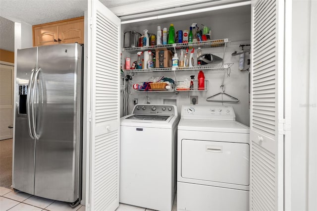 laundry area with washing machine and dryer, light tile patterned floors, and a textured ceiling