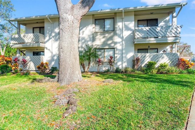 back of property with a lawn and a balcony