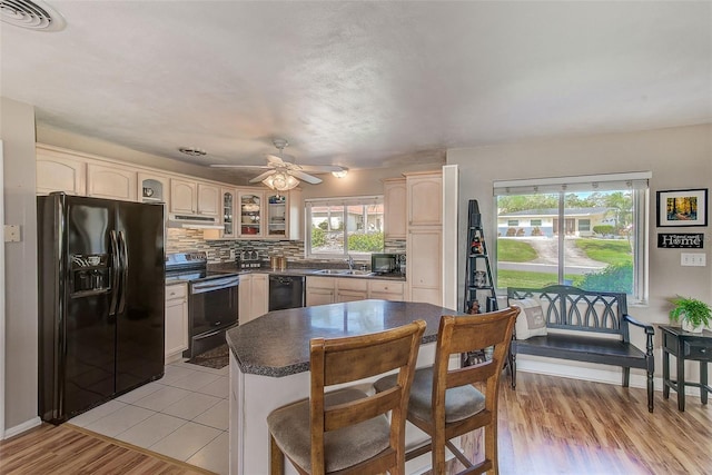 kitchen with ceiling fan, sink, decorative backsplash, black appliances, and light wood-type flooring