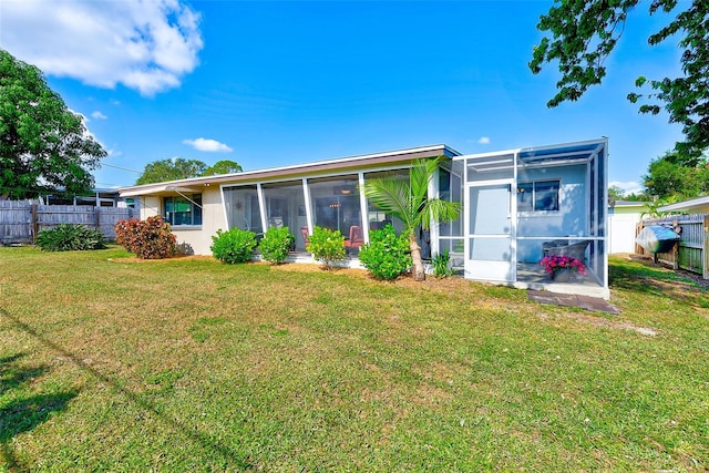 rear view of property featuring a lawn and a sunroom