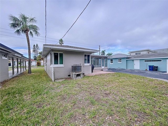 3505 Casablanca Ave, St Pete Beach, FL 33706 - rear view of house with stucco siding, a yard, and cooling unit