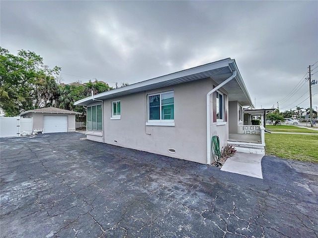 3505 Casablanca Ave, St Pete Beach, FL 33706 - view of property exterior with stucco siding, a detached garage, an outbuilding, and driveway