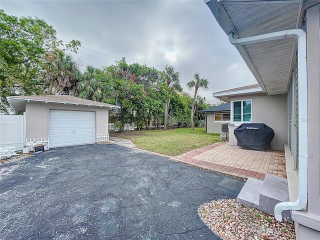 3505 Casablanca Ave, St Pete Beach, FL 33706 - view of green lawn featuring asphalt driveway, an outdoor structure, and a garage