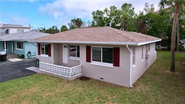 3505 Casablanca Ave, St Pete Beach, FL 33706 - rear view of house featuring roof with shingles, a yard, and stucco siding