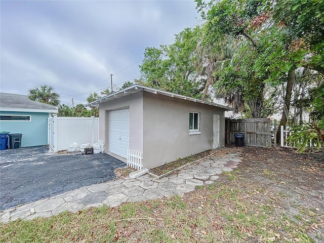 3505 Casablanca Ave, St Pete Beach, FL 33706 - view of side of home with a garage, stucco siding, asphalt driveway, and an outbuilding