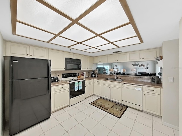 kitchen featuring cream cabinetry, sink, and black appliances