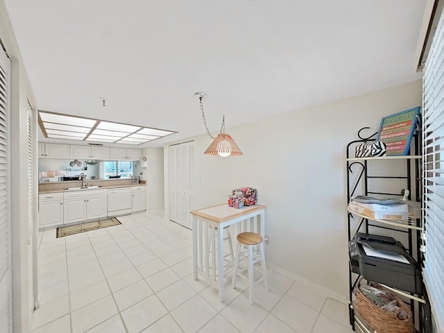 kitchen featuring dishwasher, sink, decorative light fixtures, light tile patterned flooring, and white cabinetry