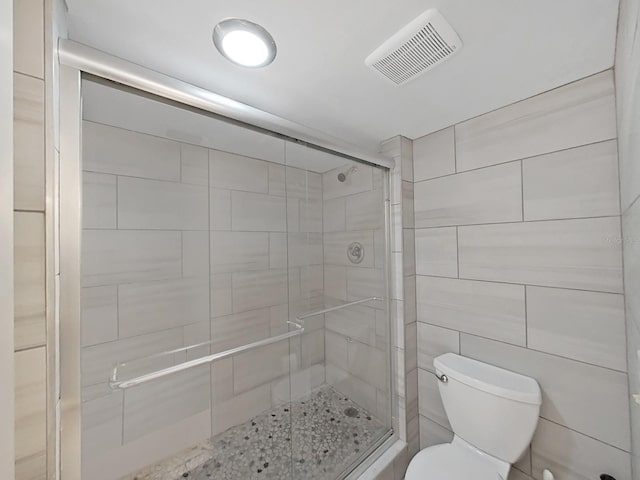 bathroom featuring an enclosed shower, tile walls, and toilet