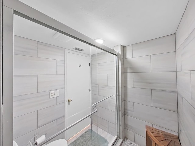 bathroom featuring toilet and a shower with door