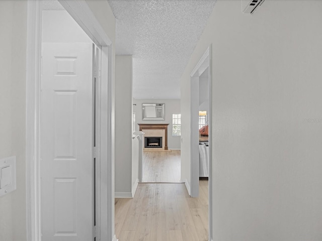 corridor featuring light hardwood / wood-style floors and a textured ceiling