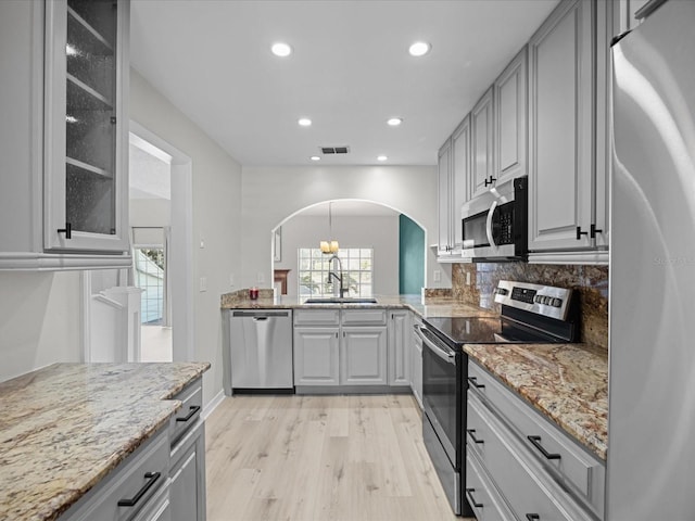 kitchen featuring appliances with stainless steel finishes, gray cabinets, light hardwood / wood-style flooring, and sink