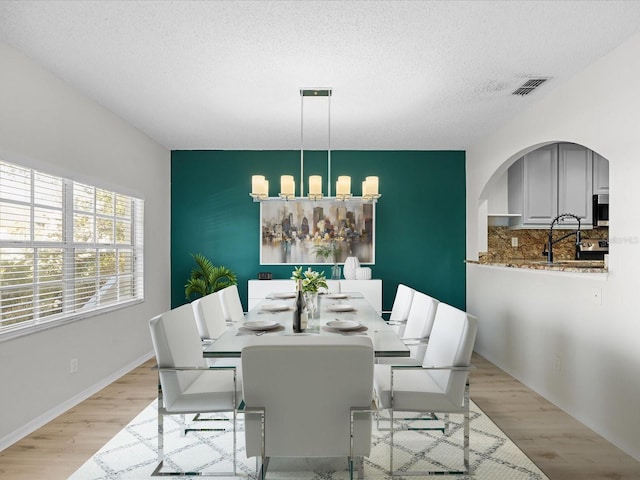 dining space featuring light hardwood / wood-style flooring, a textured ceiling, and sink