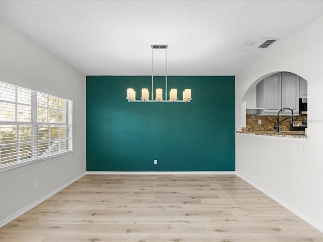 spare room with light hardwood / wood-style floors, sink, and a textured ceiling