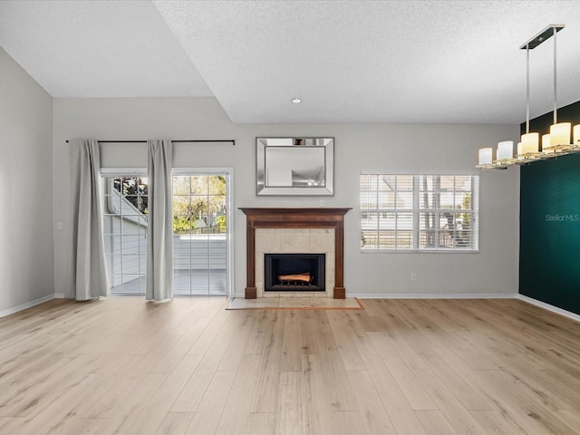 unfurnished living room featuring a tile fireplace, a textured ceiling, and light hardwood / wood-style floors