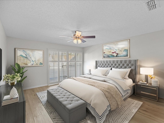 bedroom with ceiling fan, a textured ceiling, and light wood-type flooring