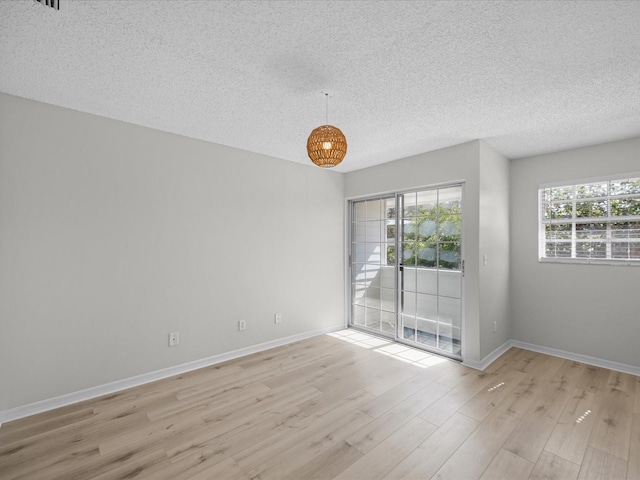 spare room featuring a textured ceiling and light hardwood / wood-style flooring