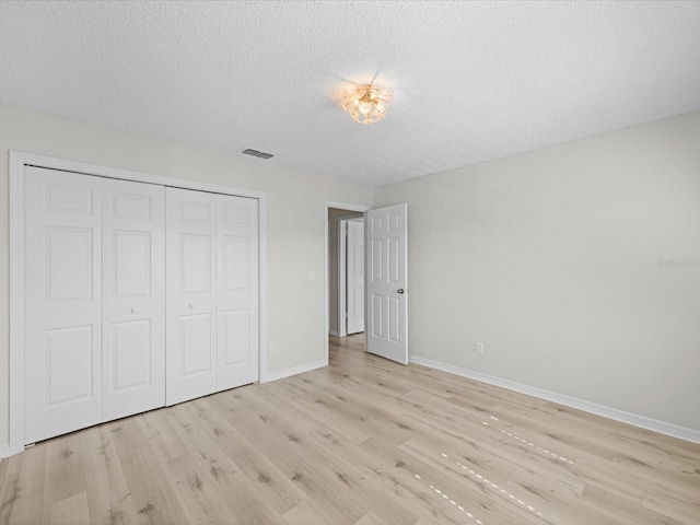 unfurnished bedroom featuring a closet, light hardwood / wood-style floors, and a textured ceiling