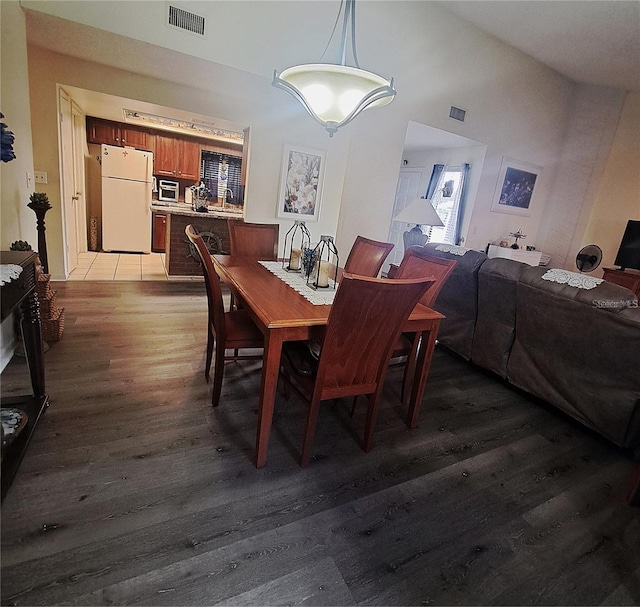 dining space with wood-type flooring and high vaulted ceiling