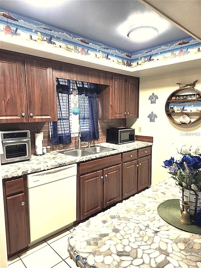 kitchen featuring sink, backsplash, light tile patterned floors, white dishwasher, and dark brown cabinets