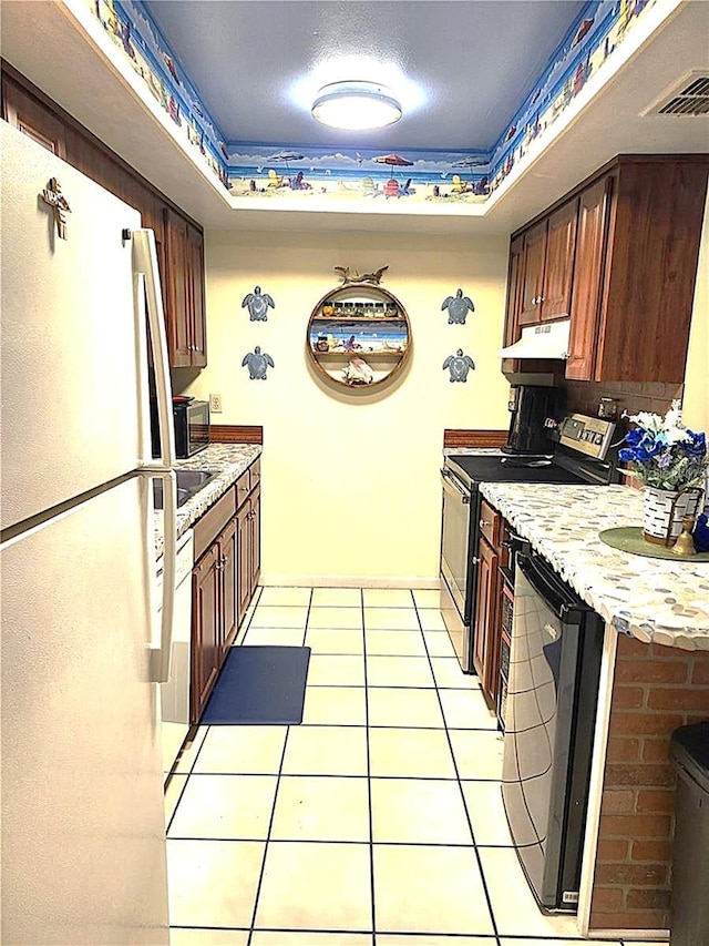 kitchen with stainless steel appliances, light tile patterned floors, and a textured ceiling