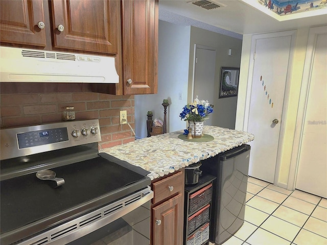 kitchen featuring light tile patterned floors, decorative backsplash, stainless steel range with electric cooktop, and refrigerator