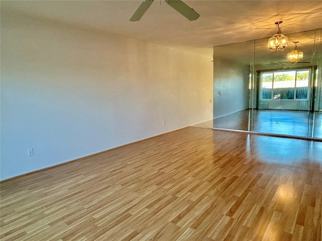 unfurnished room featuring light hardwood / wood-style floors and ceiling fan with notable chandelier