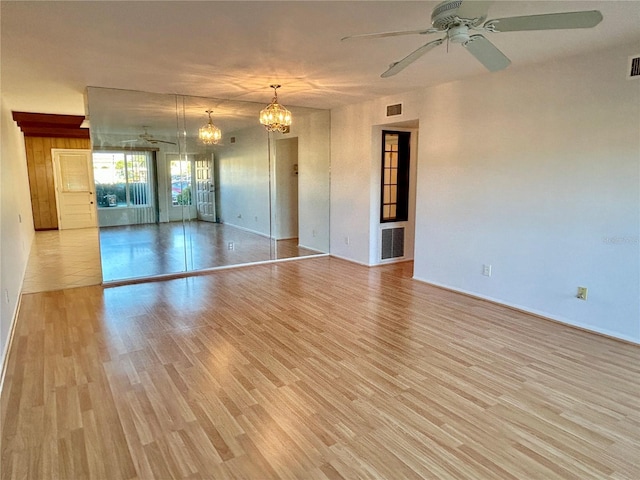 empty room featuring light hardwood / wood-style floors and ceiling fan with notable chandelier