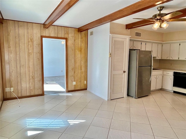 kitchen with wooden walls, ceiling fan, black dishwasher, beam ceiling, and stainless steel refrigerator