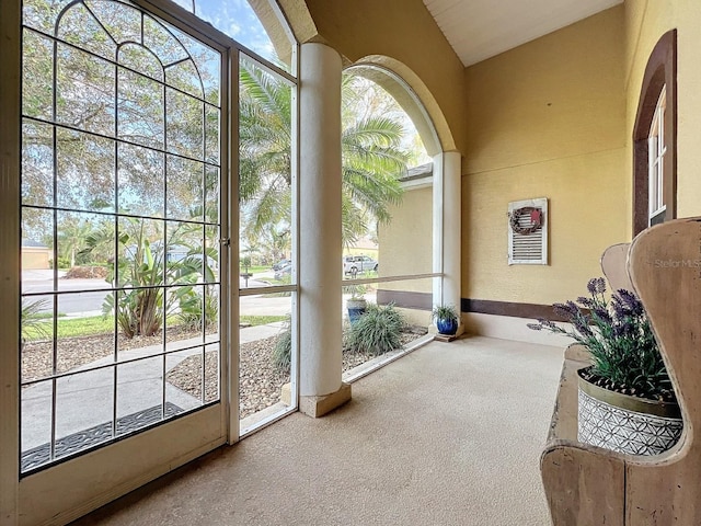 doorway with carpet, plenty of natural light, and vaulted ceiling