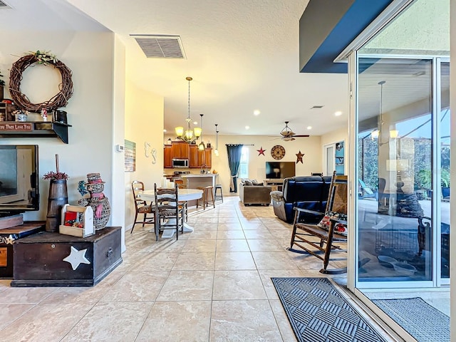 tiled living room with ceiling fan with notable chandelier