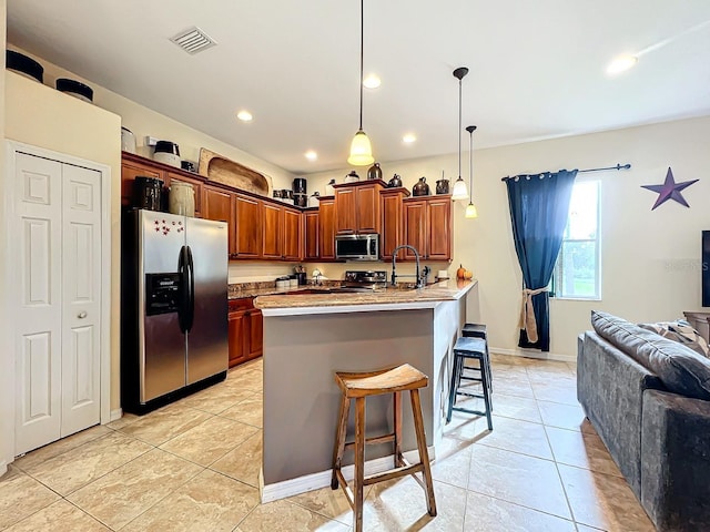 kitchen with hanging light fixtures, stainless steel appliances, light stone counters, a kitchen bar, and light tile patterned floors