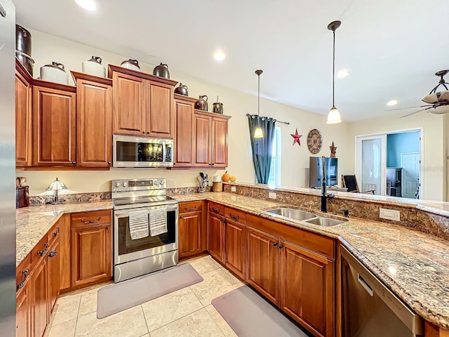 kitchen featuring sink, hanging light fixtures, ceiling fan, light stone countertops, and stainless steel appliances