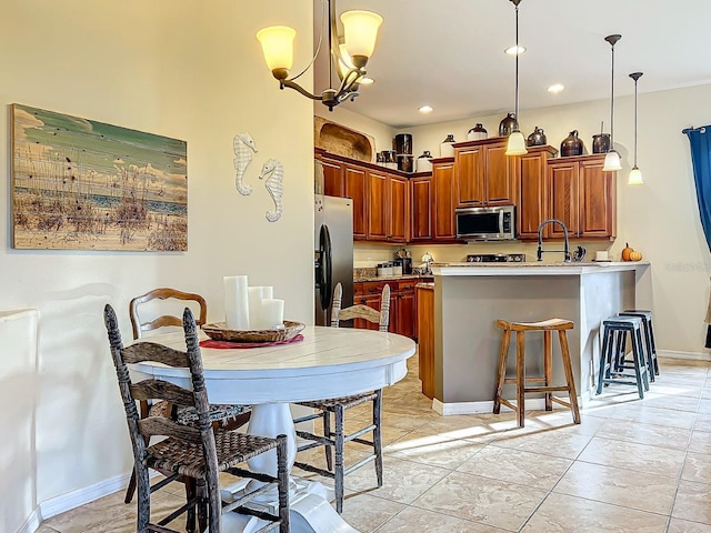 kitchen with kitchen peninsula, a chandelier, pendant lighting, a kitchen bar, and appliances with stainless steel finishes