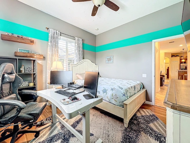 bedroom featuring stainless steel fridge, light wood-type flooring, and ceiling fan