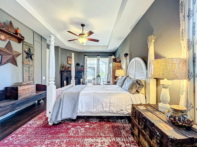 bedroom with hardwood / wood-style flooring, ceiling fan, and a tray ceiling